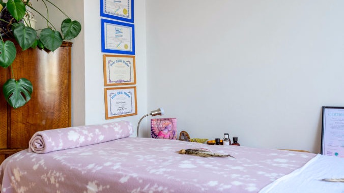 En lyserød briks med planter og diplomer i baggrund